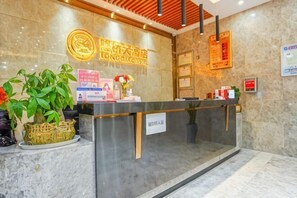 A hotel reception desk with a marble wall, a neon sign, and a potted plant. - Longqiao Hotel (Yichang Yiting Three Gorges Airport) (Yichang)