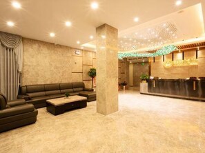 A hotel lobby with a reception desk, a sofa, and a coffee table. - Longqiao Hotel (Yichang Yiting Three Gorges Airport) (Yichang)