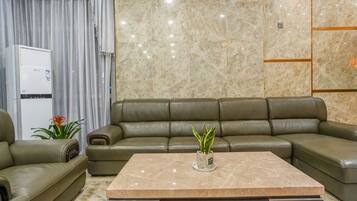 A modern living room with a sectional sofa, a marble coffee table, and a white appliance in the background.