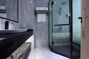 A modern bathroom with a glass-enclosed shower, a black sink, and a marble wall.