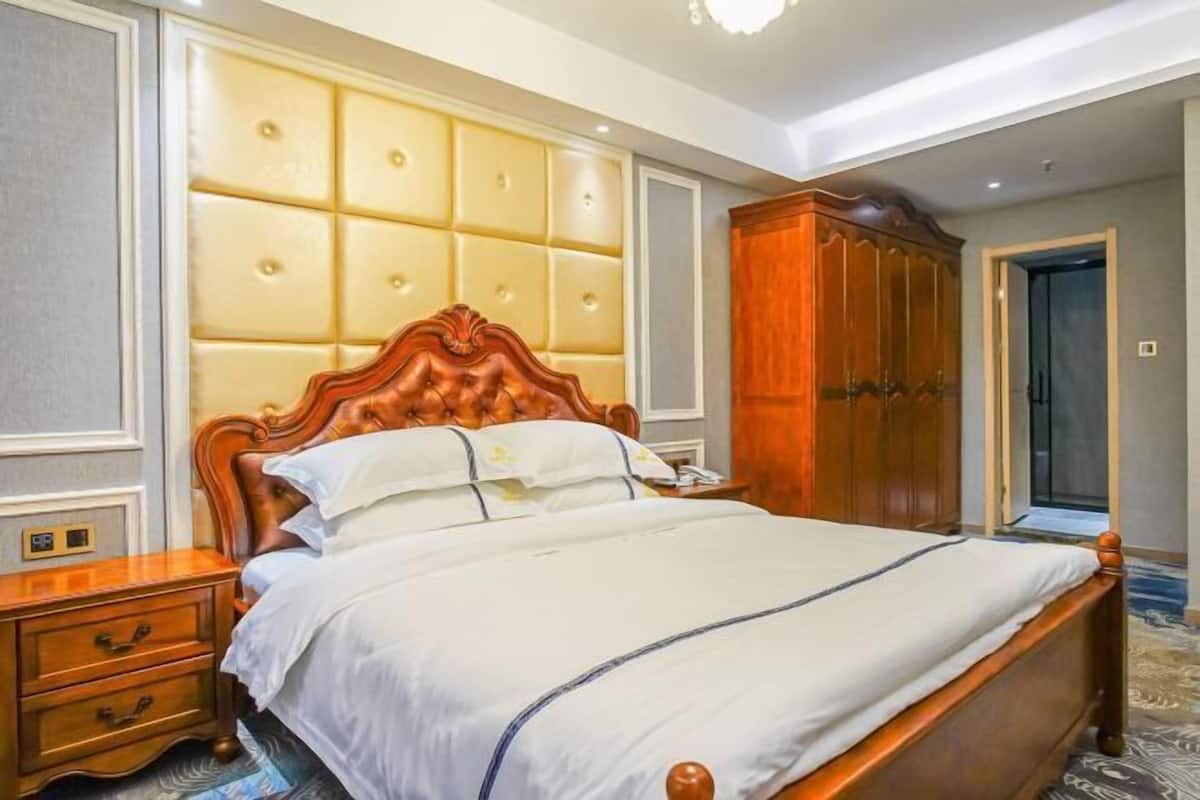A hotel room with a large bed, a wooden wardrobe, and a nightstand.