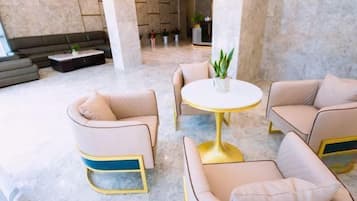 A lobby with a round table and two sofas, a dark-colored sofa, and a plant on the table.