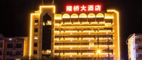 A multi-story hotel with a prominent sign and illuminated windows at night.