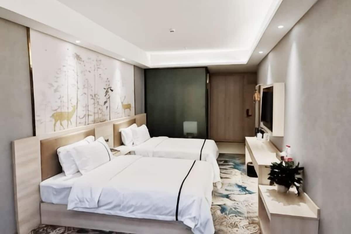 A hotel room with two beds, a TV, a desk, and a decorative wall piece.