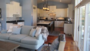 A modern kitchen with white cabinets, a central island, and a dining area with a sofa and chairs. - Fish Creek Beautiful Downtown Condo Sleeps 8 (Fish Creek)