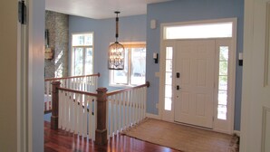 A hallway with a wooden staircase, a white door, and a stone wall. - Fish Creek Beautiful Downtown Condo Sleeps 8 (Fish Creek)