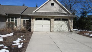 A two-story house with a stone facade, a gabled roof, and a garage with two doors. - Fish Creek Beautiful Downtown Condo Sleeps 8 (Fish Creek)