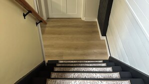 Una escalera con alfombra estampada que lleva a una puerta blanca con cerradura electrónica.
