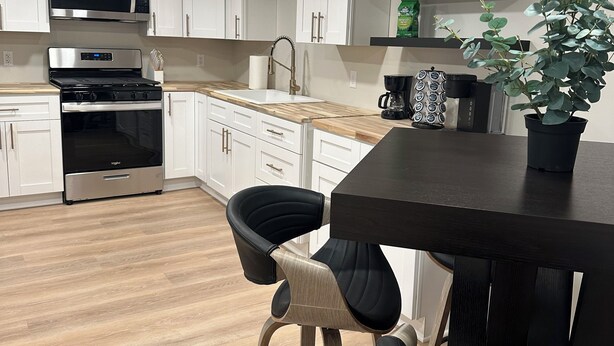 Una cocina moderna con armarios blancos, electrodomésticos de acero inoxidable y encimera de madera.