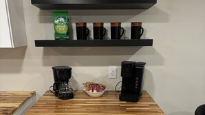 Una cocina con cafetera, un tazón de cápsulas de café y una máquina de café sobre la encimera.