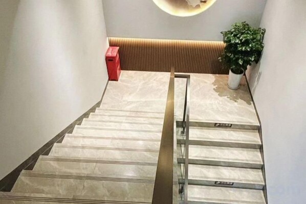 A staircase with a handrail, a red box, and a potted plant.