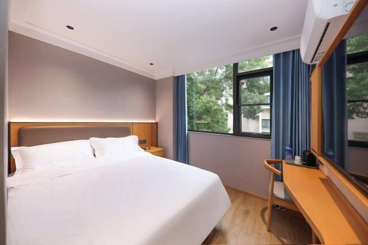 A hotel room with a bed, a desk, and a window.
