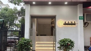 A hotel entrance with a sign reading "Miduo Hotel" and a green sign with the number "864". - Miduo Hotel (Shanghai)