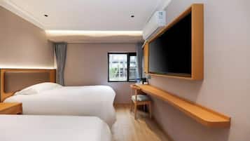 Una habitación de hotel con dos camas, un escritorio, un televisor y una ventana.