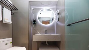 A modern bathroom with a toilet, a sink with a mirror, and a shower. - Miduo Hotel (Shanghai)