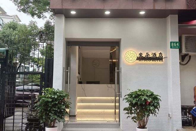 Entrada de hotel con mostrador de recepción, una escalera que da al interior y un cartel con el nombre del hotel.