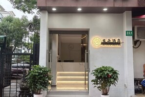 A hotel entrance with a reception desk, a staircase leading inside, and a sign indicating the hotel's name. - Miduo Hotel (Shanghai)