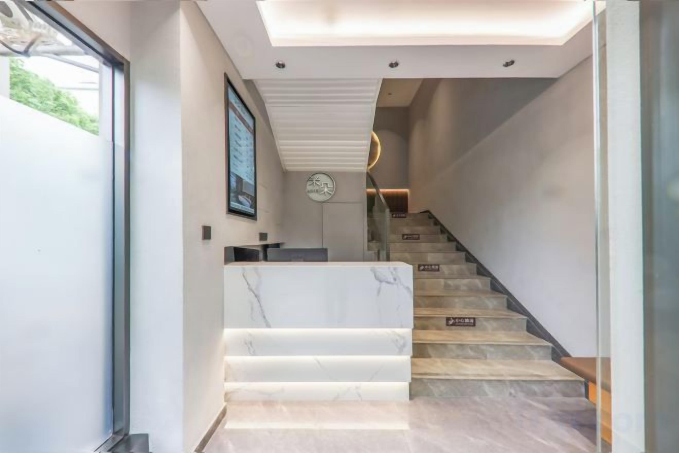 Una escalera moderna con peldaños de mármol y barandilla de vidrio, que conduce a un segundo piso.