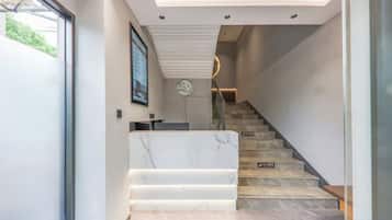 Una escalera moderna con peldaños de mármol y barandilla de vidrio, que conduce a un segundo piso.
