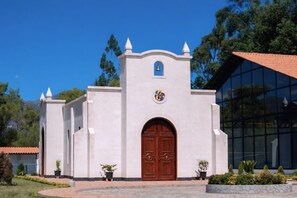 Eine Kirche mit weißer Fassade, einem Glockenturm und einer großen Holztür.