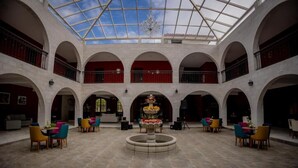 A spacious atrium with a central fountain, multiple seating areas, and a glass ceiling allowing natural light.