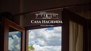 A view from a room at Casa Hacienda Boutique Hotel, featuring a balcony with a wrought iron railing and a glimpse of a traditional building with a red-tiled roof and a white facade.