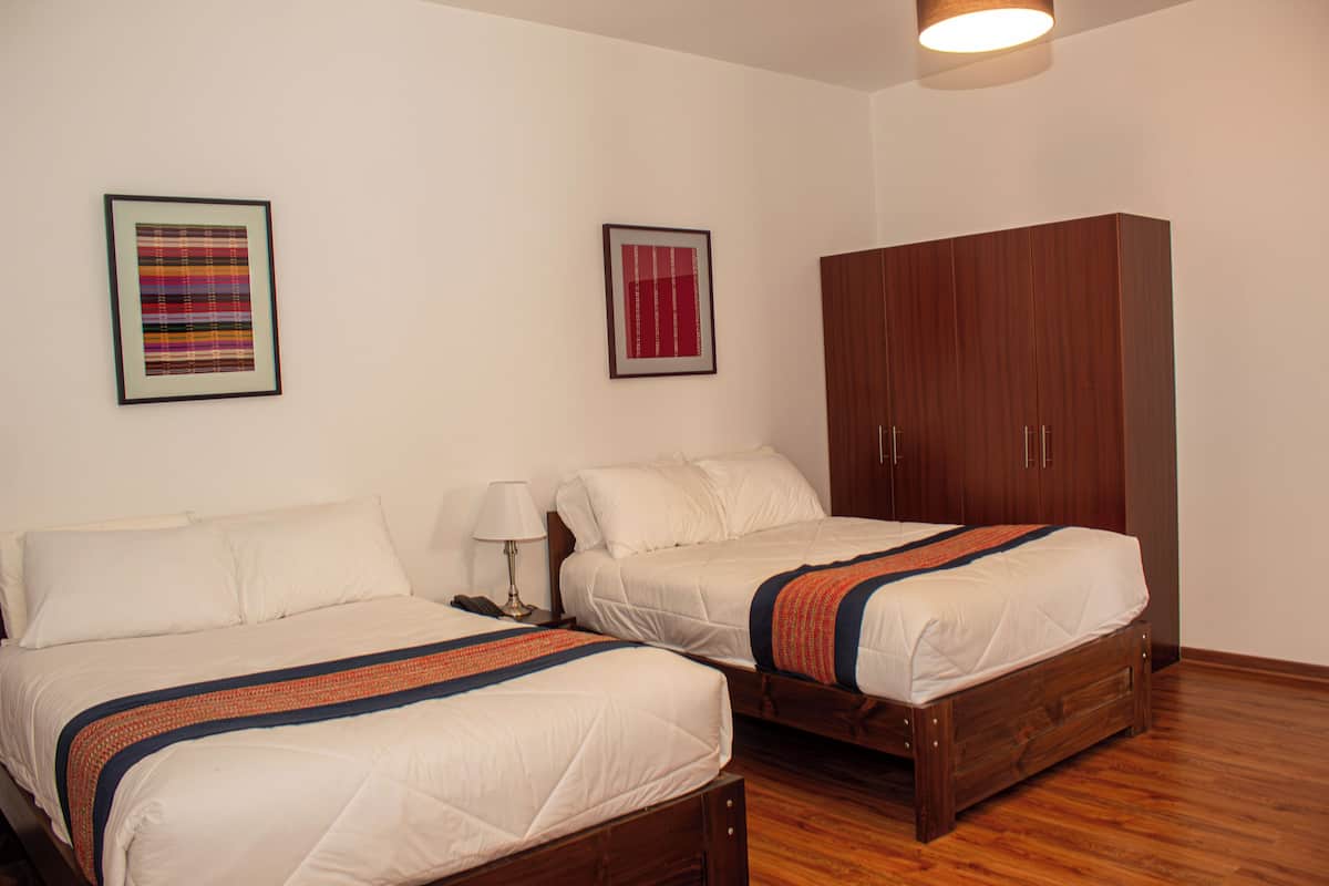 Een kamer met twee bedden, een kledingkast en twee ingelijste foto's aan de muur.