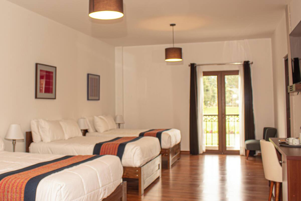 Een hotelkamer met twee bedden, een bureau, een stoel en een balkon.