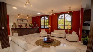 A spacious living area with white sofas, a central coffee table, and large windows.