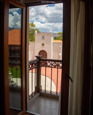 Vista desde una habitación del Hotel Boutique Casa Hacienda, con un balcón de barandilla de hierro forjado y una pincelada de un edificio tradicional con techo de tejas rojas y fachada blanca.