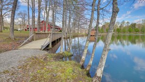 A wooden dock leading to a house by a calm lake, surrounded by trees. - Fire Pit + Game Room: Lakefront Escape in Trenton! (Trenton)