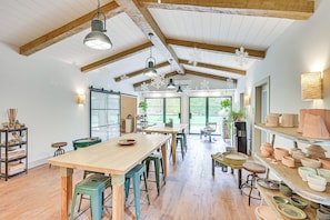 Enjoy the airy feel of this room with high ceilings and large windows, featuring a central table and comfortable seating.