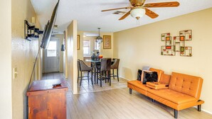 A living room with a wooden ceiling fan, a sofa, and a dining area with chairs and a table.