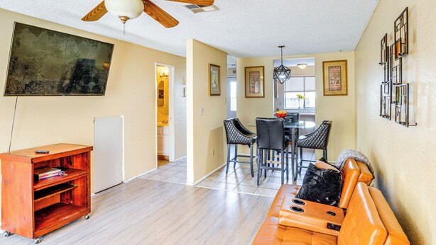 A living room with a ceiling fan, a dining area with chairs, and a sofa.