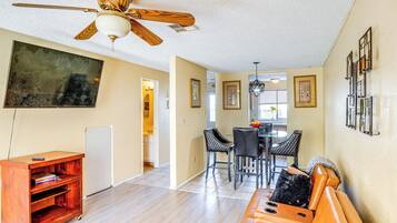 Relax in this spacious living area with a dining table, sofa, and mounted TV.