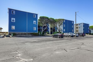 A parking lot with several cars parked in front of a blue building with multiple windows and balconies. - Oceanfront Gem w/ Views in North Topsail Beach (North Topsail Beach)