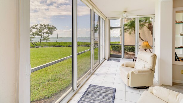 A spacious room with large sliding glass doors leading to a balcony, a beige sofa, and a lamp. - Walk to Stuart Beach: Resort Condo w/ Water View! (Stuart)