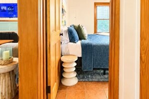Un dormitorio con cama, mesita de noche y ventana.