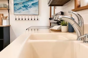 A kitchen with a modern sink, a painting on the wall, and a set of hooks above the sink. - Sleeps 6. Kayaks. Boat Dock. Big Yard (Crystal River)