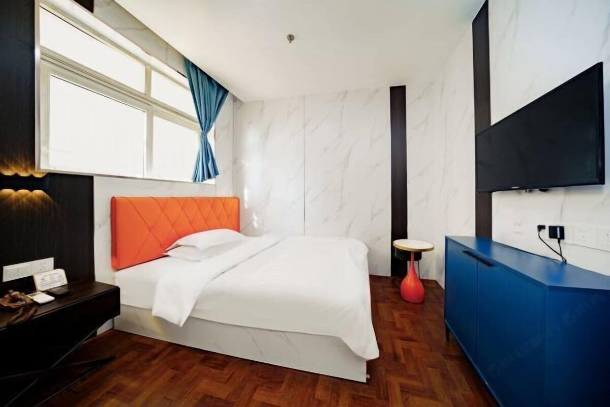 A hotel room with a bed, a desk, a TV, and a blue cabinet.