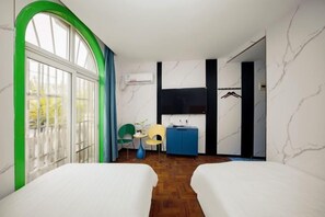 Ein Hotelzimmer mit zwei Betten, einem kleinen Schreibtisch, einem Stuhl, einem Kleiderschrank und einem großen Fenster mit Vorhängen.