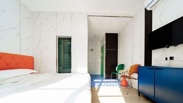 Een moderne hotelkamer met een bed, een blauwe kast en een groene stoel.