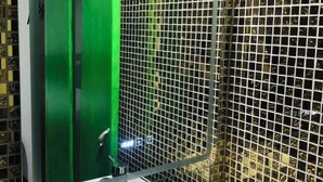 Een groene deuren van een lift, met een metalen gaaswand.