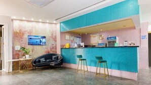 Een moderne receptie met een turquoise betegelde balie, een zwarte bank en twee groene barstoelen.