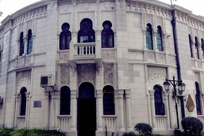 Un bâtiment historique doté de détails architecturaux raffinés, de nombreuses fenêtres en arc de cercle et d’une entrée centrale.