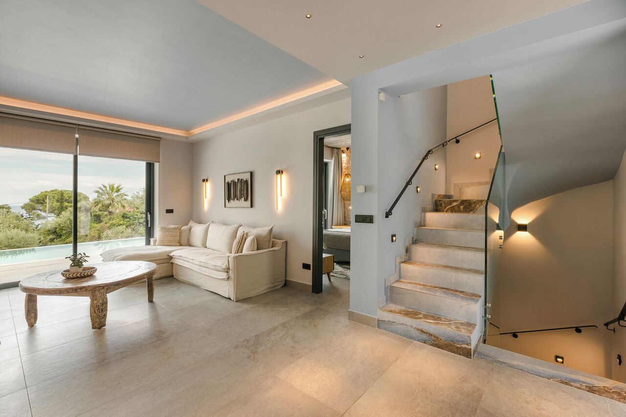 A modern living room with a large window, a staircase, and a sofa.