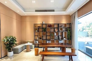 Un interior moderno con una mesa de madera, bancos, una estantería y plantas en macetas.