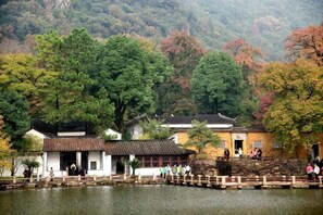 A traditional building with a wooden structure, a stone bridge, and a lake. - Greentree Inn Jiangsu Suzhou International Film City South Jinshan Road Express Hotel (Suzhou)