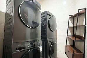 Stacked appliances, including a washing machine and dryer, and a metal shelving unit. - Greentree Inn Jiangsu Suzhou International Film City South Jinshan Road Express Hotel (Suzhou)