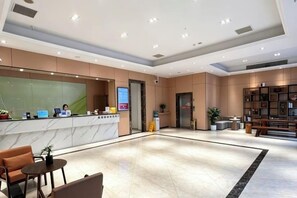 A hotel reception area with a marble counter, seating, and a bookshelf.